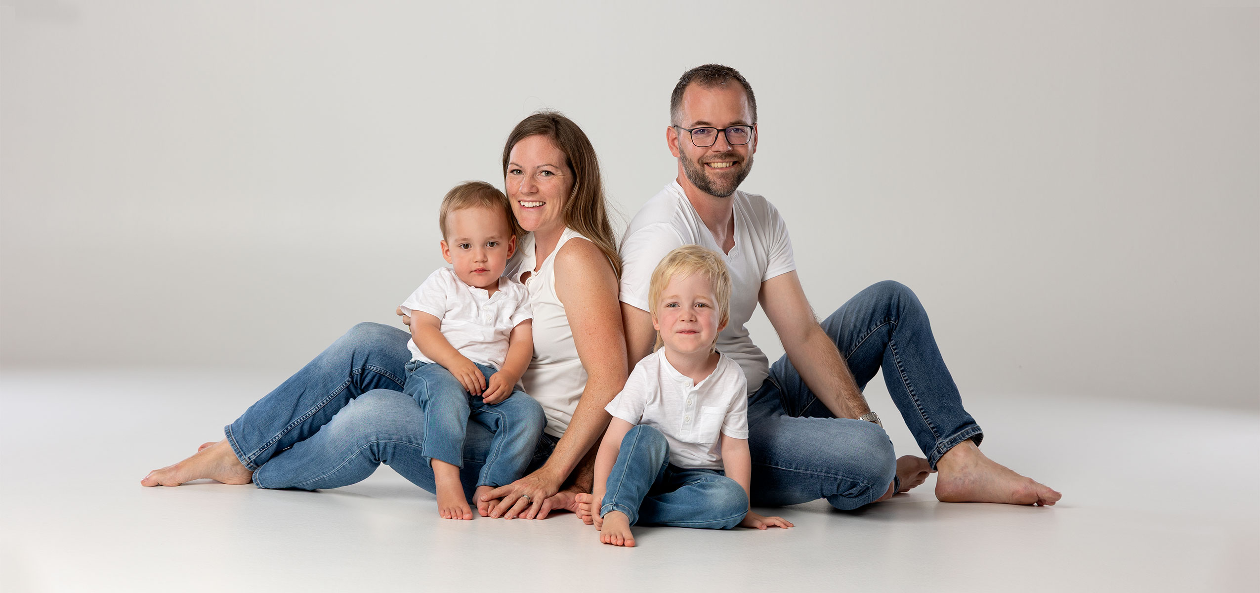 Natürliches Familienfoto in Zofingen mit Eltern und zwei Kindern im Fotostudio Fokus, hell und liebevoll fotografiert