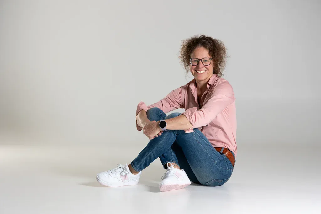 Natürliches Portraitshooting in Zofingen mit Frau sitzend vor hellem Hintergrund und freundlicher Bildwirkung.