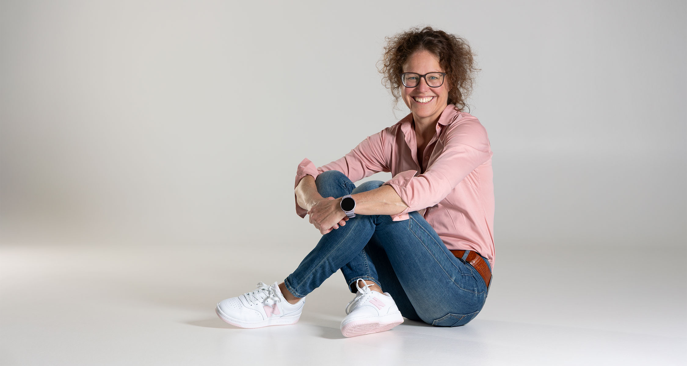 Natürliches Portraitshooting in Zofingen mit Frau sitzend vor hellem Hintergrund in entspannter Studioatmosphäre.